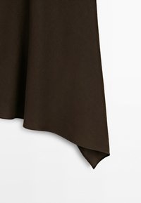 Brown fabric with a pointed, asymmetrical hem hanging against a white background.