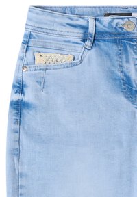Light blue denim jeans with a small beige knitted fabric item partially visible in the front right coin pocket.