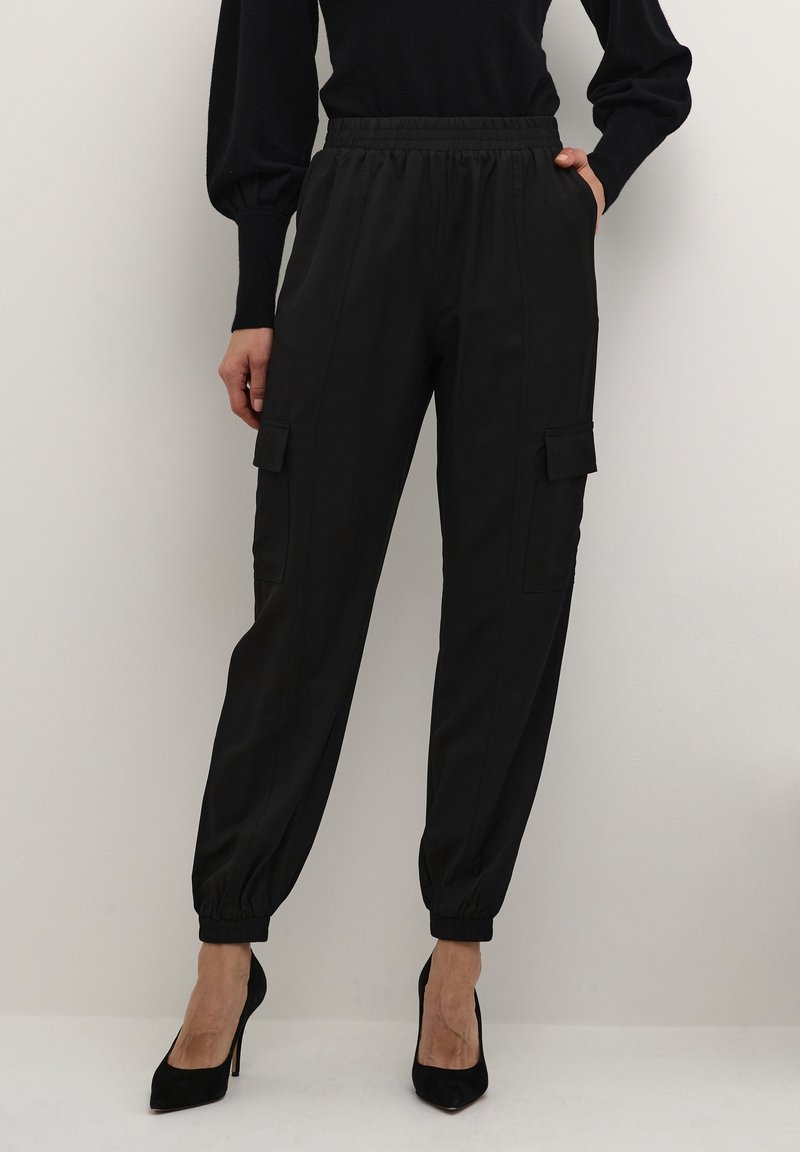 Black cargo pants with an elastic waistband and tapered cuffs. Features two side pockets and two front cargo pockets, made from smooth fabric.