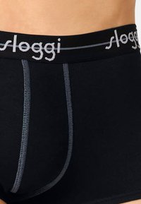 Schwarze Baumwoll-Boxershorts mit einem grauen elastischen Bund, der das "sloggi"-Logo, dekorative Nähte und eine glatte Textur aufweist.