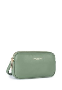 Borsetta in pelle verde con zip e hardware dorato. Presenta una superficie liscia e bordi arrotondati. Marchio "LANCASTER PARIS" impresso in oro.