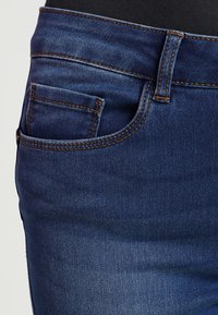 Tmavěmodré džíny z denimu s klasickým designem, pěti kapsami a kontrastním prošíváním na pasu a kapsách.