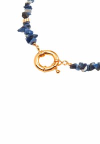Collana di chip in sodalite con chiusura circolare dorata. Le pietre mostrano diverse sfumature di blu con una finitura liscia e lucidata.