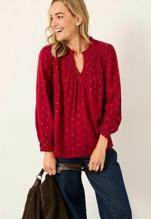 Red, long-sleeve blouse with gathered neckline and button detailing. Features subtle metallic patterns, loose fit, and elasticized cuff.