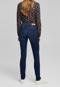 Slim-fit blå jeans i denim, med bakfickor, ett midjeband med en lapp och en enkel fåll. Bärs med en blommig långärmad topp.