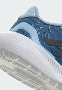 Sinine spordijalats, millel on tekstureeritud võrgust pealiskate, helesinised aktsendid ning valge, mustriline kummist tallaosa, millel on haardemustrid.