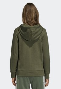 Olivgrön hoodie med snörning i huvan, med ett texturerat tyg. Designen inkluderar en känguruficka och ribbade ärmslut och nederkant.