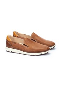 Zapatos de cuero marrón de tipo slip-on con textura perforada en la parte superior, detalles en color marrón claro y suela de goma blanca.