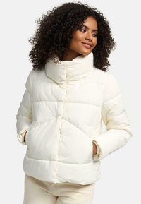 Doudoune blanche avec un col montant, design matelassé en losanges, et boutons-pression sur le devant. Texture douce et poches latérales.