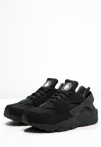 Svarta träningsskor med ovandel i mjukt tyg, perforerade detaljer, dämpad sula och en framträdande logotyp på tungan.