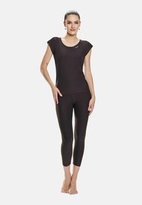 Top aderente nero con maniche corte, abbinato a leggings capri coordinati. Tessuto morbido e elasticizzato con un marchio sottile sulla parte superiore.