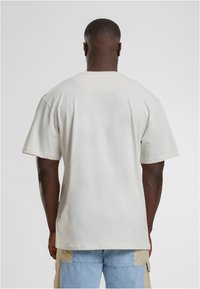 Triko s krátkým rukávem a kulatým výstřihem v světle béžové tkanině, které se vyznačuje volným střihem, hladkým povrchem a bez viditelných vzorů nebo akcentů.