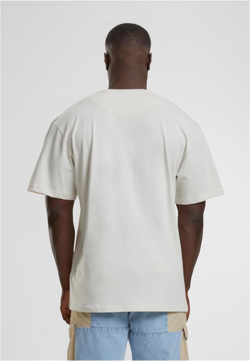 Triko s krátkým rukávem a kulatým výstřihem v světle béžové tkanině, které se vyznačuje volným střihem, hladkým povrchem a bez viditelných vzorů nebo akcentů.