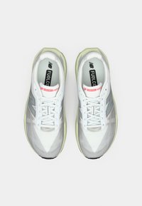 White athletic shoes with a gradient design, rubber sole, mesh upper, and reflective accents; features a padded collar and laces for support.