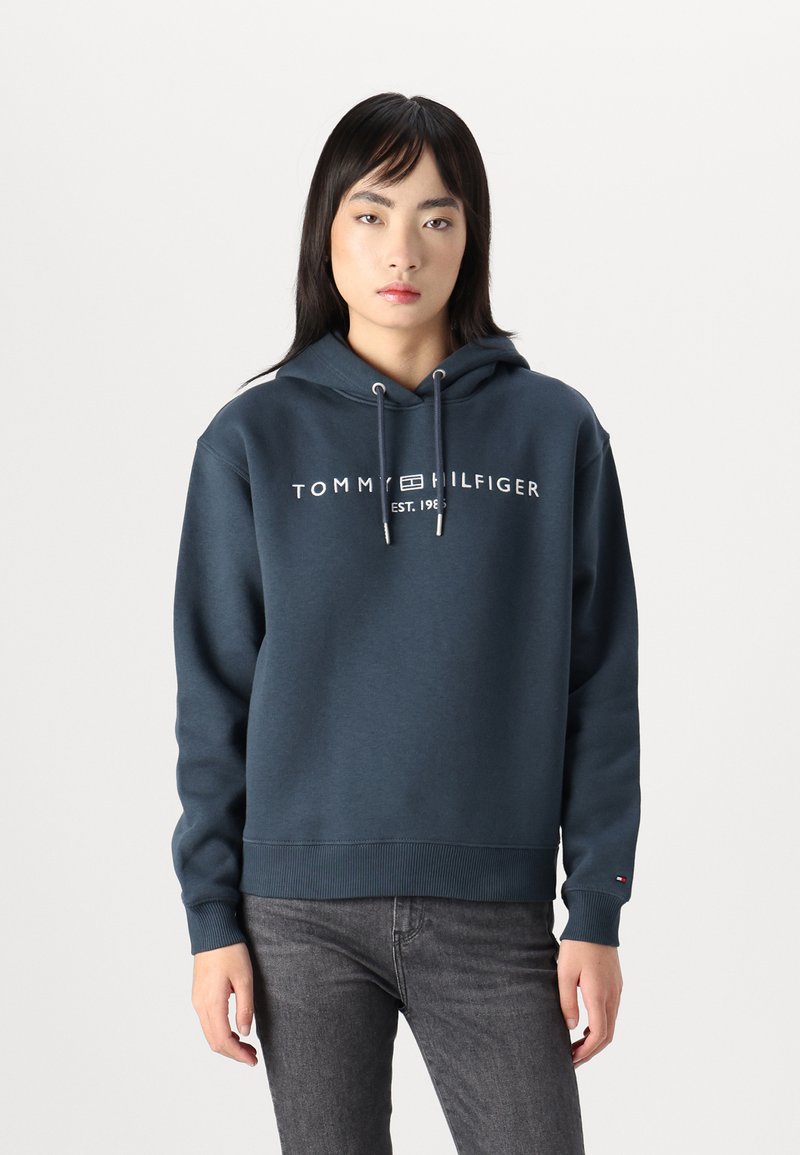 Sweatshirt azul-marinho com capuz e mangas compridas, com punhos e bainha canelados; apresenta o logótipo "TOMMY HILFIGER" em branco, confeccionado em material suave.