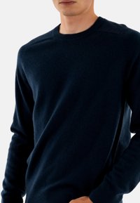 Maglione a trama blu navy realizzato in materiale morbido, dotato di collo tondo, maniche lunghe e polsini e orlo ribattuti.