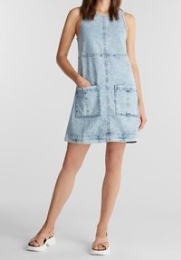 Vaaleansininen farkumekko, jossa on muotoiltu yläosa ja levenevä helma. Mukana on kaksi suurta etutaskua ja erivärinen tikkaus. Pehmeä rakenne ja hihaton malli.