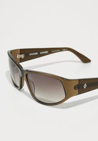Brown plastic sunglasses with gradient lenses. Wide frames feature a subtle logo on the temples and a smooth, shiny texture.