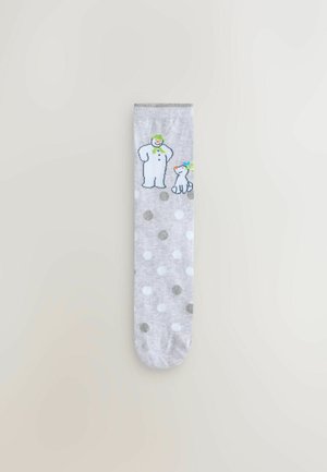 Graue Socke mit weißen und metallischen Punkten, die ein Grafik von einem Schneemann und einem Hund zeigt. Hergestellt aus weichem Stoff mit einer glatten Textur.