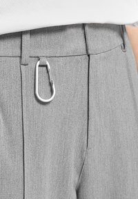Pantalones grises con una tela texturizada, un corte ajustado y un mosquetón plateado sujeto a la cintura.