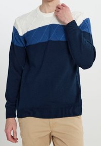 Marineblauer Strickpullover mit weiß-blauem Paneeldesign, das im oberen Bereich ein strukturiertes Rautenmuster und gerippte Bündchen aufweist.