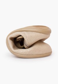 Chaussure beige flexible pliée en deux, montrant une tige en tissu texturé et une semelle en caoutchouc souple, mettant en valeur son design pliable.