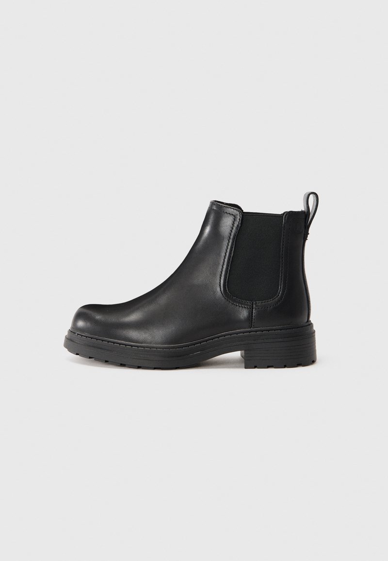 Bottine Chelsea en cuir noir avec panneau élastique sur les côtés, tirant à l'arrière et semelle épaisse crantée, présentée sur un fond clair et uni.
