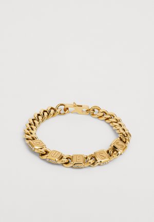 Goldener Armreif mit Blockbuchstaben, die "GUESS" buchstabieren, und Strassakzenten. Die Glieder haben eine glatte, polierte Oberfläche. Sichere Verschlussmechanik.