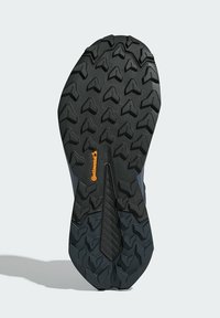 Suela de zapato de goma negra con un patrón de textura y banda de rodadura multidireccional. Presenta un logo "Continental" en color naranja cerca del centro.