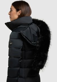 Sort pufferjakke med høj krave og blød sort pelskant. Har et quiltet design, logo-patch og vandafvisende materiale.