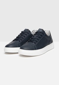 Sneakers in pelle blu navy con suole in gomma bianca, punta rotonda e lacci in tessuto. Presentano un design minimalista e un dettaglio del logo sulla linguetta.