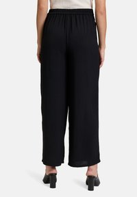 Zwarte wijde broek met een elastische tailleband. Gemaakt van een textuurstof, de broek heeft een losse pasvorm en een enkel-lange snit.