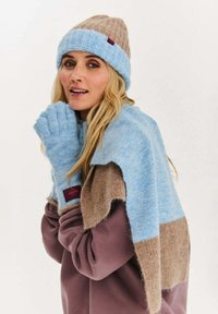 Modrá a hnědá pletená čepice, ladící šála a bezprsté rukavice. Jemná textura s barevným blokovým vzorem. Štítky na šále a rukavicích.