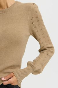 Tansweater van zacht gebreid materiaal. Heeft ribgebreide manchetten en een textuurpatroon op de mouwen, met een klassiek crew neck ontwerp.