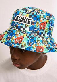 Bucket-Hut mit einem bunten Sonic the Hedgehog-Muster, das Charaktere und Ringe zeigt, aus stoff mit einem strukturierten Schirm und Logodetail.