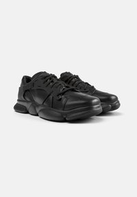 Black leather sneakers with a rounded design, textured rubber sole, and lace-up closure. Includes perforations for ventilation and a rear tab.