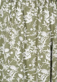 Zelena krila iz blaga z belim cvetličnim vzorcem. Ima nabran elastičen pas, tekoč dizajn in različne botanične ilustracije.