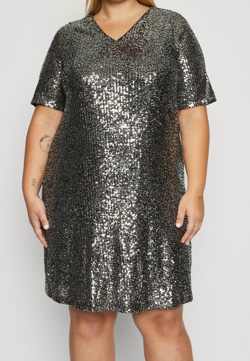 Robe à manches courtes et col en V, recouverte de sequins noirs et argentés réfléchissants. Coupe ample avec un ourlet arrondi, créant un aspect texturé.