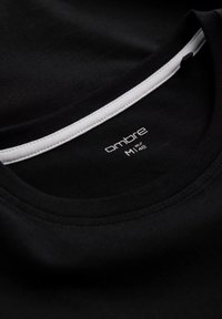 Schwarzes T-Shirt mit Rundhalsausschnitt, das am Kragen einen weißen Saum hat. Der Stoff sieht glatt und weich aus und zeigt das Markenlogo.
