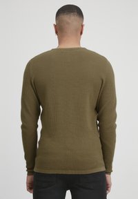 Oliven grønn langermet strikkegenser med teksturert mønster, rund hals, og tettsittende mansjetter. Minimalistisk design, ensfarget bak.