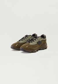 Green and brown sneakers featuring a suede and mesh upper, round laces, and black rubber outsole with ridges for traction.