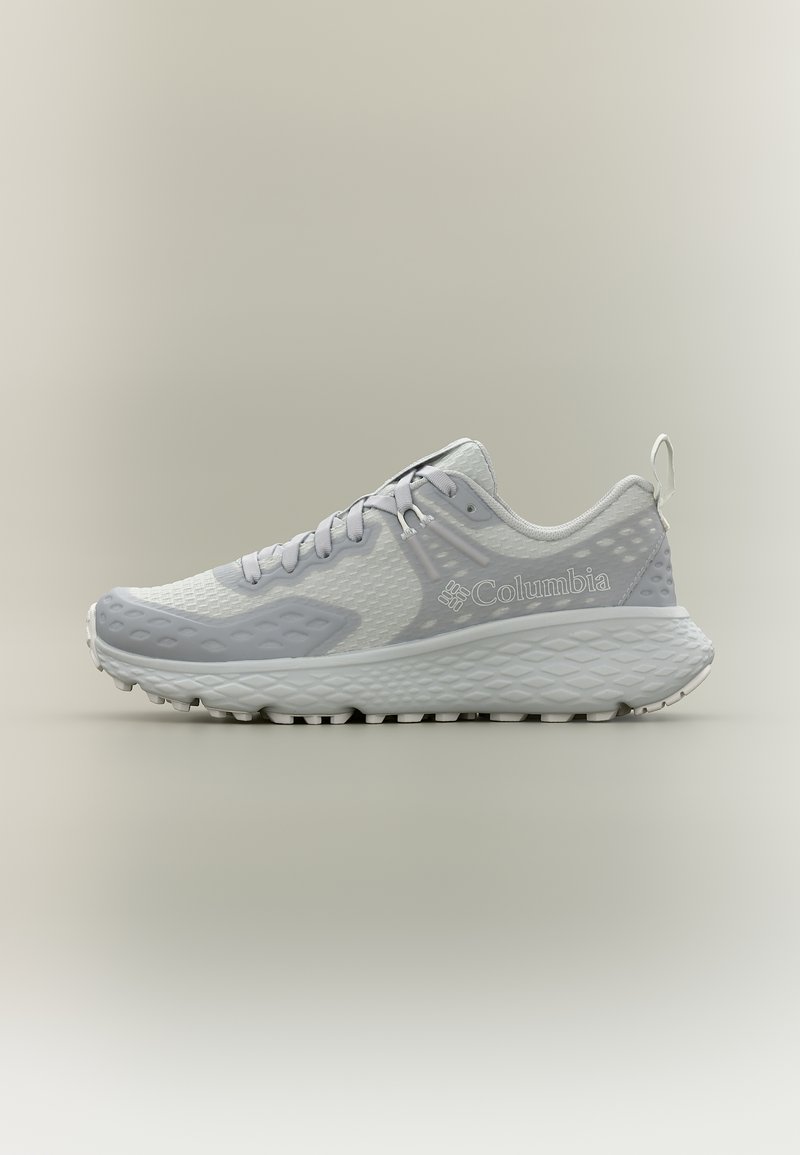 Ανοιχτό γκρι και λευκό αθλητικό παπούτσι Columbia για τρέξιμο με υφασμένο πάτο και επάνω μέρος από δίχτυ, λογότυπο στο πλάι και κλείσιμο με κορδόνια, εμφανιζόμενο σε προφίλ σε ουδέτερο φόντο.