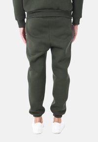 Pantaloni jogger verde oliva realizzati in un morbido misto cotone, dotati di polsini e vita a costine, con una vestibilità rilassata e senza motivi visibili.