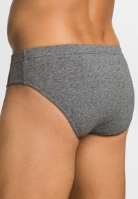 Slip grigi in cotone con una texture liscia, a taglio medio, e una vita elasticizzata con un accento rosso a contrasto sul lato.