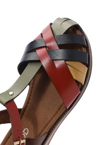Multi-colored leather sandal featuring an intricate woven design with straps in green, red, navy, and yellow, set on a brown sole.