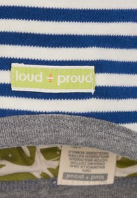 Top in cotone a righe con strisce orizzontali blu e bianche. Collo grigio con un'etichetta verde "loud + proud" e un interno a fantasia.