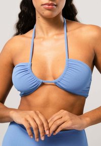Ljusblå bikiniöppning med samlad tyggdesign, tunna axelremmar och sömlös finish, som framhäver en slät textur och minimal hårdvara.