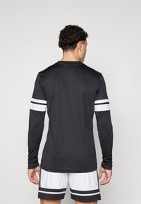 Zwarte trainingsshirt met lange mouwen en witte strepen op de mouwen, gemaakt van lichtgewicht stof, met een ronde halslijn en een slim-fit ontwerp.