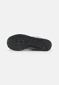 Suela de goma negra con surcos profundos y patrones de tracción; material superior gris con acabado texturizado y área de puntera reforzada.
