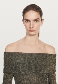 Schulterfreies Oberteil aus dunkel-metallischem Strick mit strukturierter Oberfläche. Figurbetonte Passform mit weiter Halslinie und langen Ärmeln.